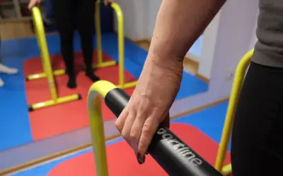 Rehabilitacja po niedowładzie nóg: ćwiczenia na poręczach. Dłoń trzymająca uchwyt.
