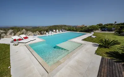Lussuosa piscina in Sardegna, con vista mare e colline. Ideale per rilassarsi dopo un viaggio in traghetto.