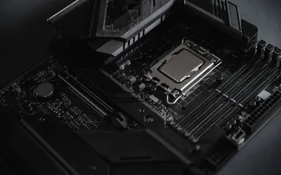 Czarna płyta główna z procesorem i slotami RAM. Widoczny radiator i elementy chipsetu.