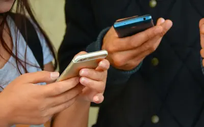 Dwie osoby trzymają telefony. Zastanawiasz się, jak sprawdzić, gdzie ostatnio logował się telefon?