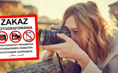 Kobieta z aparatem ignoruje znak zakaz fotografowania.