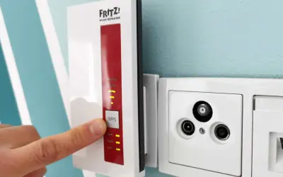 Fritz! WLAN Repeater verbessert das Signal, um **WLAN durch Betondecke** zu leiten. Ein Finger drückt auf die WPS-Taste.