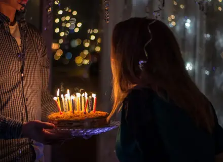 Urodzinowy tort ze świeczkami dla 14 latki, w tle migoczące światełka.
