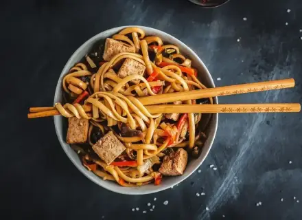 Miseczka z makaronem udon, tofu i warzywami, gotowa do podania. Idealny przepis na pad udon.