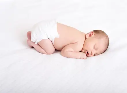 Śpiące dziecko w pieluszce, które niedługo otrzyma szczepienie na rotawirusy. Zdrowie maluszka jest najważniejsze.