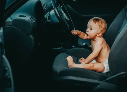 Maluch siedzi za kierownicą, jakby zastanawiał się, od kiedy dziecko może jeździć z przodu.