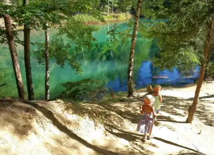 Dwie dziewczynki w słomkowych kapeluszach idą ścieżką nad turkusowe jezioro. Idealne miejsce, gdzie z dzieckiem na weekend.