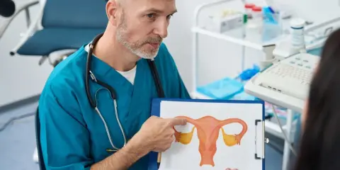 Lekarz omawia z pacjentką budowę macicy i możliwości leczenia mięśniaków macicy, wskazując na rysunek.