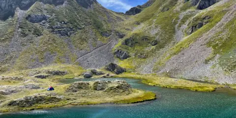 Un accampamento solitario ai laghetti di Ponteranica, tra montagne verdi e acque cristalline.