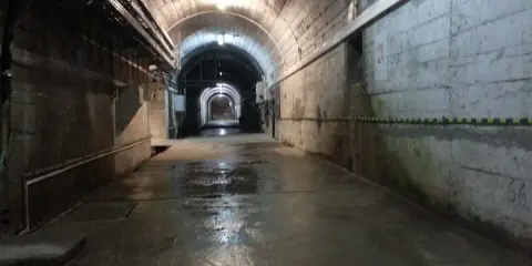 Wnętrze tunelu podczas zwiedzania elektrowni Solina. Mokra posadzka odbija światło lamp.