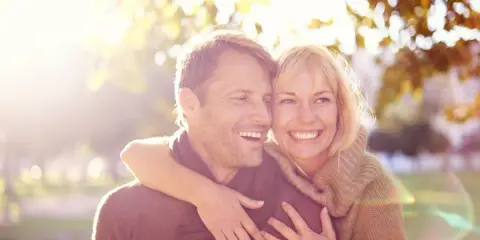 Un couple souriant, peut-être traversant une crise de la cinquantaine, mais l'infidélité semble loin. Lumière dorée d'automne.