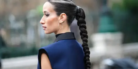 Eine Frau mit einem dicken, geflochtenen Zopf und Highlights. So kann man haare einfach stylen für einen eleganten Look.