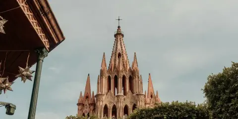 Imponująca iglica kościoła w San Miguel, otoczona zielenią, z ozdobnymi gwiazdami zwisającymi z zadaszenia.