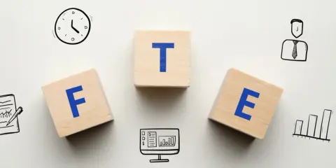 Klocki z literami F, T, E. Obok zegar, wykresy, komputer i pracownik. Jak obliczyć FTE?