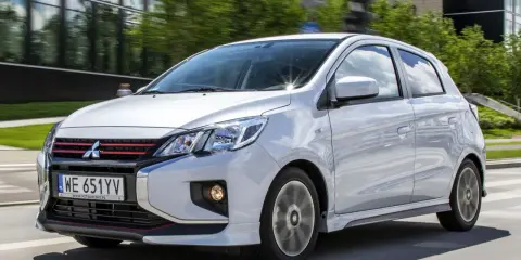 Srebrny Mitsubishi Space Star z czerwonymi akcentami na grillu i zderzaku jedzie po drodze.
