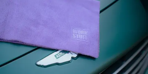 Fioletowa mikrofibra z logo Work Stuff na masce zielonego samochodu. Idealna do pielęgnacji lakieru.
