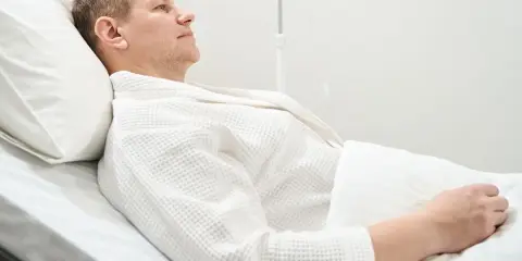 Mężczyzna w białym szlafroku leży w szpitalnym łóżku, przygotowując się do usunięcia pęcherza moczowego.