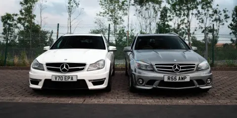 Dwa Mercedesy C63 AMG W204, biały i szary, stoją obok siebie na parkingu.