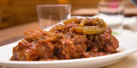 Un succulento piatto di coda alla vaccinara, cotta lentamente in un ricco sugo di pomodoro con verdure.