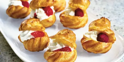 Små petit choux fyllda med vispgrädde och toppade med hallon eller jordgubbar. En härlig dessert!