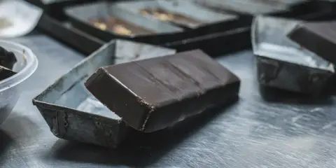 Une tablette de chocolat posée sur une petite boîte métallique. Idéal pour apprendre comment faire des copeaux de chocolat.