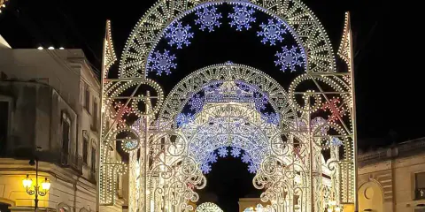 Archi luminosi illuminano la notte di Galatina per la festa di San Pietro e Paolo, creando un'atmosfera magica.