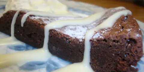 En bit chokladkaka med vispad grädde och vit chokladsås. En härlig vit kladdkaka som smälter i munnen.