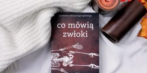 Książka "Co mówią zwłoki" Sue Black, opowieści antropologa sądowego, leży obok zapalonej świecy i jesiennych liści.
