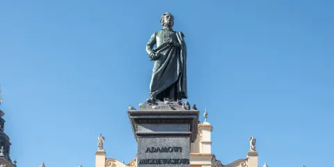 Pomnik Mickiewicza, symbol romantyczności, na tle Sukiennic. Streszczenie epoki w kamieniu i architekturze.