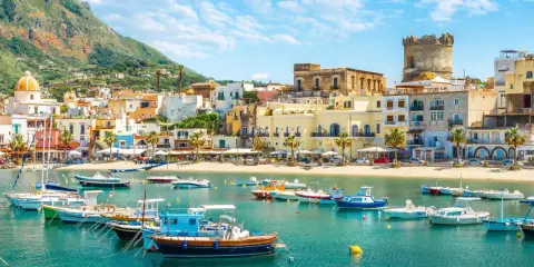 Un incantevole scorcio di Ischia con bambini che sognano gite in barca. Case colorate, mare azzurro e un castello medievale.