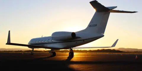 Ein weißer Privatjet steht im Sonnenuntergang auf dem Rollfeld. Verschiedene privatjets modelle sind auf dem Markt, aber dieser hier strahlt Luxus aus.