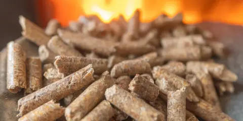 Granulés de bois prêts pour l'installation d'un poêle à granule, avec des flammes chaudes en arrière-plan.