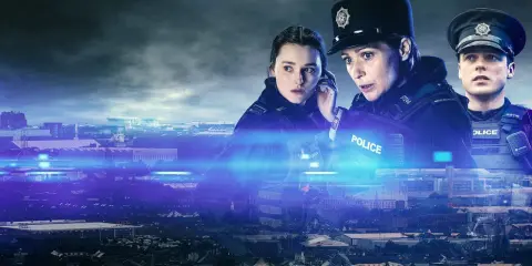 Poliser i uniform över en stadssiluett, upplyst av blåa ljus.