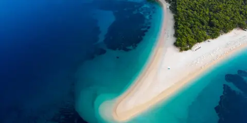 Widok z lotu ptaka na Zlatni Rat w Chorwacji. Plaże otoczone turkusowym morzem i zielonym lasem.