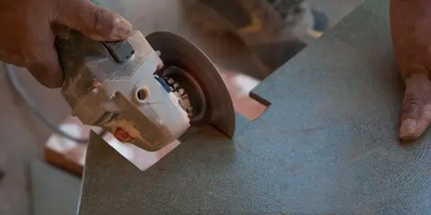 Mano sujetando una radial para cortar azulejos con precisión.