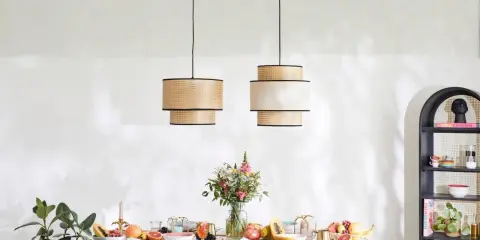 Dwie lampy z rattanu nad stołem z owocami i kwiatami. Inspiracja, jak dobrać lampy do salonu i jadalni.