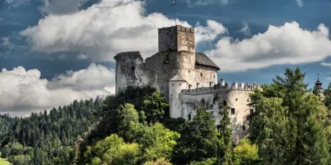 Zamek w Niedzicy, jedna z głównych atrakcji Nowego Targu, majestatycznie wznosi się na wzgórzu, otoczony zielenią.