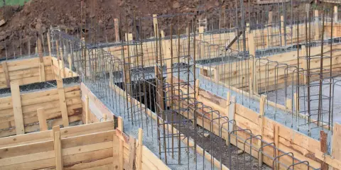 Drewniane deskowanie fundamentów z zbrojeniem stalowym, gotowe do zalania betonem.