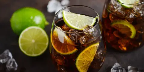 Orzeźwiający Cuba Libre z kostkami lodu i plasterkami limonki, gotowy do wypicia.