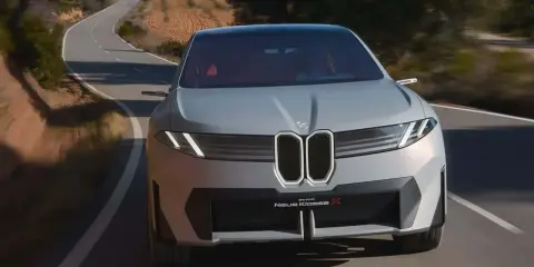 La BMW Neue Klasse X sfreccia su una strada tortuosa, un'icona di design futuristico.