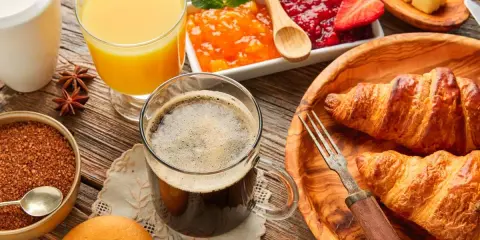 Pyszne śniadanie kontynentalne: świeże croissanty, dżemy, masło, sok pomarańczowy i kawa. Idealny początek dnia!