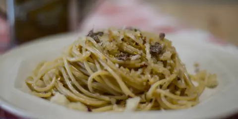 Un piatto di spaghetti conditi con pangrattato tostato, aglio, peperoncino e formaggio grattugiato, un classico della pasta mollicata.