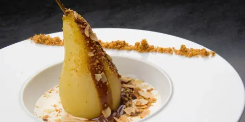 Un poire pochée, nappée de chocolat et amandes effilées, servie avec une crème légère. Un dessert poire chocolat rapide et gourmand.