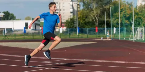 Młody biegacz na bieżni podczas zajęć sportowych dla młodzieży.