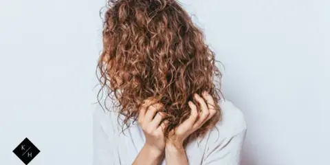 Frauen mit einer voluminösen Dauerwelle, die ihre Hände durch die Locken gleiten lassen.