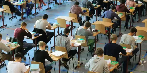 Schüler konzentriert bei einer Prüfung. Die Wortherkunft des Abiturs ist lateinisch, was "weggehen" bedeutet.