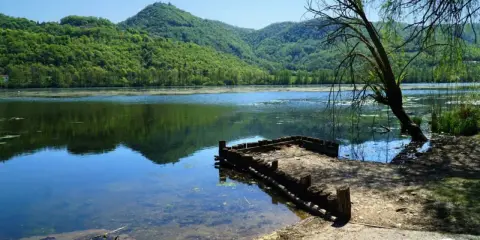 Un pontile in legno sul lago di Fimon, circondato da colline verdi e alberi.