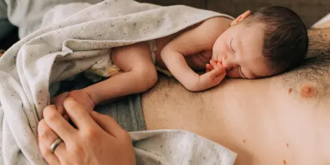 Ein Neugeborenes schläft auf der Brust seines Vaters. Die Frage "wie werde ich ein guter vater" wird hier durch diese liebevolle Szene beantwortet.