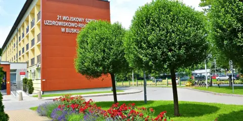 Sanatorium MSW Busko Zdrój z czerwonymi różami i lawendą w słoneczny dzień.