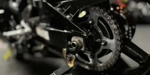 Zbliżenie na tylne koło motocykla z widocznym łańcuchem i zębatką. Pytanie: jaki smar do łańcucha motocyklowego?